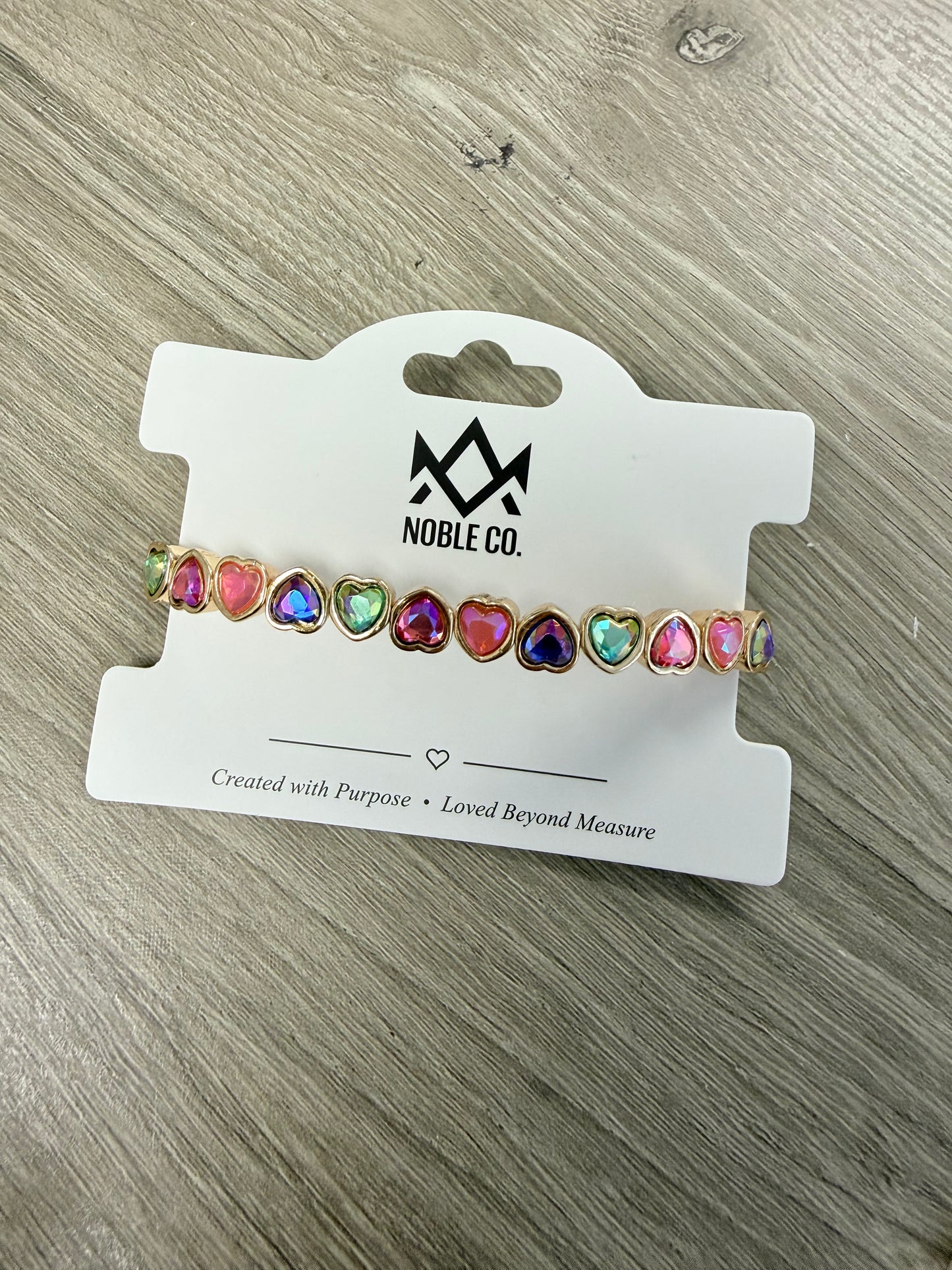Poppy Rainbow Heart Crystal Stretch Bracelet by Noble Co. featuring multicolor faceted heart-shaped crystals in polished gold-tone settings.