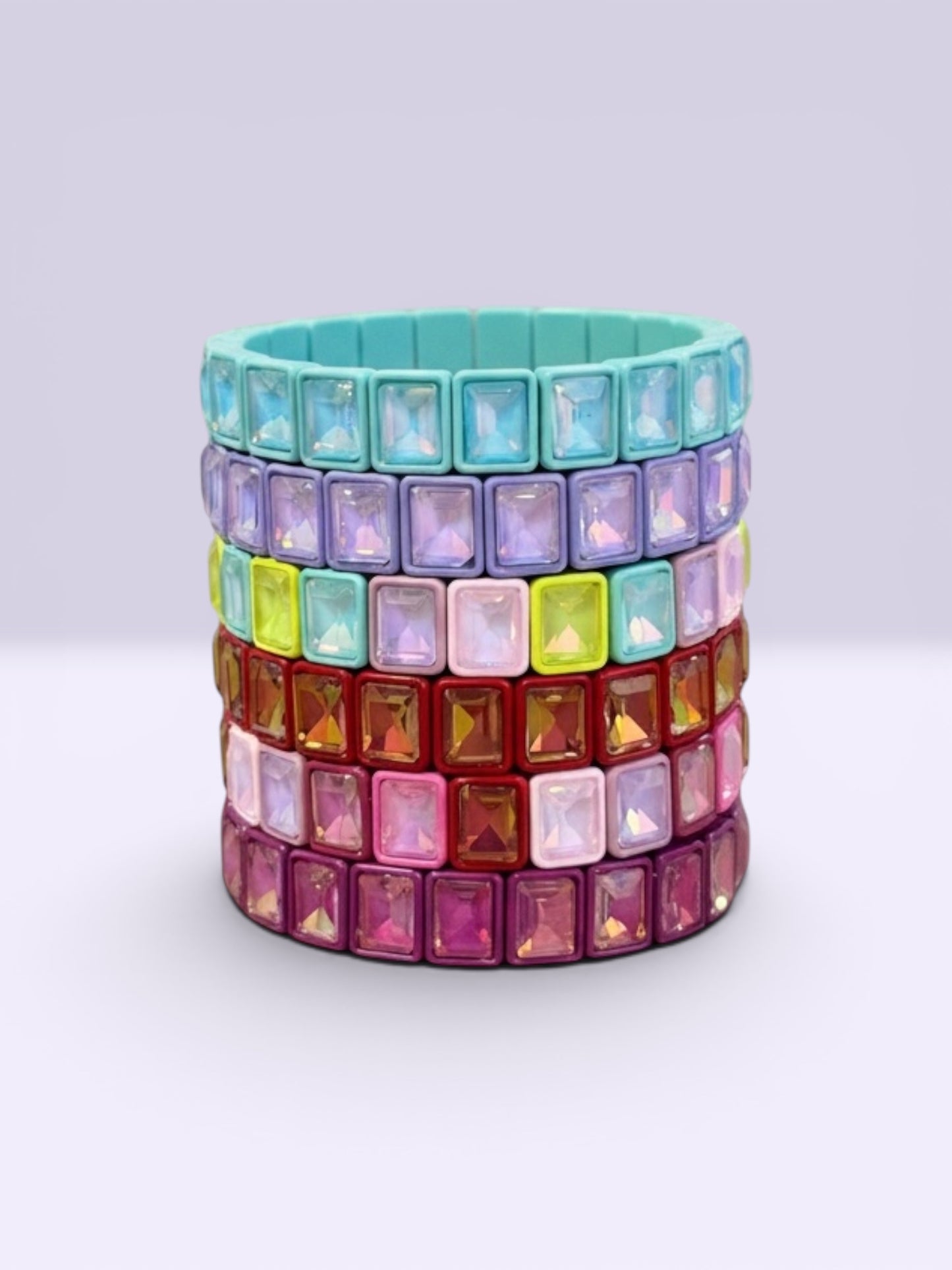 Stack of colorful gemstone bracelets on a light gray background