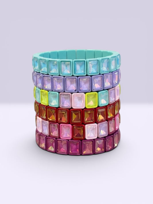 Stack of colorful gemstone bracelets on a light gray background