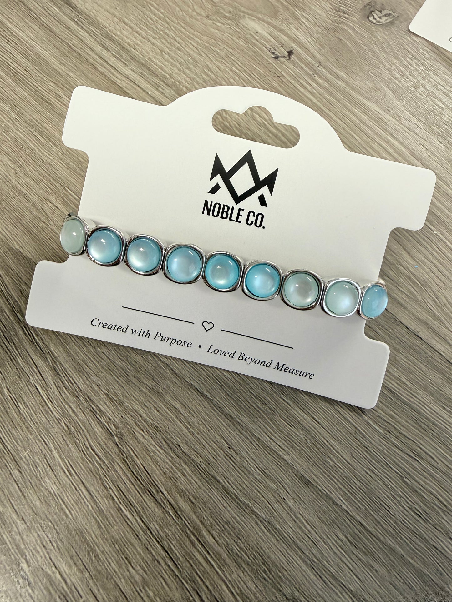 Audrey Sea Glass Stretch Bracelet by Noble Co. featuring soft blue sea glass-inspired cabochon stones in polished silver-tone settings.