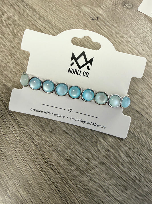Audrey Sea Glass Stretch Bracelet by Noble Co. featuring soft blue sea glass-inspired cabochon stones in polished silver-tone settings.