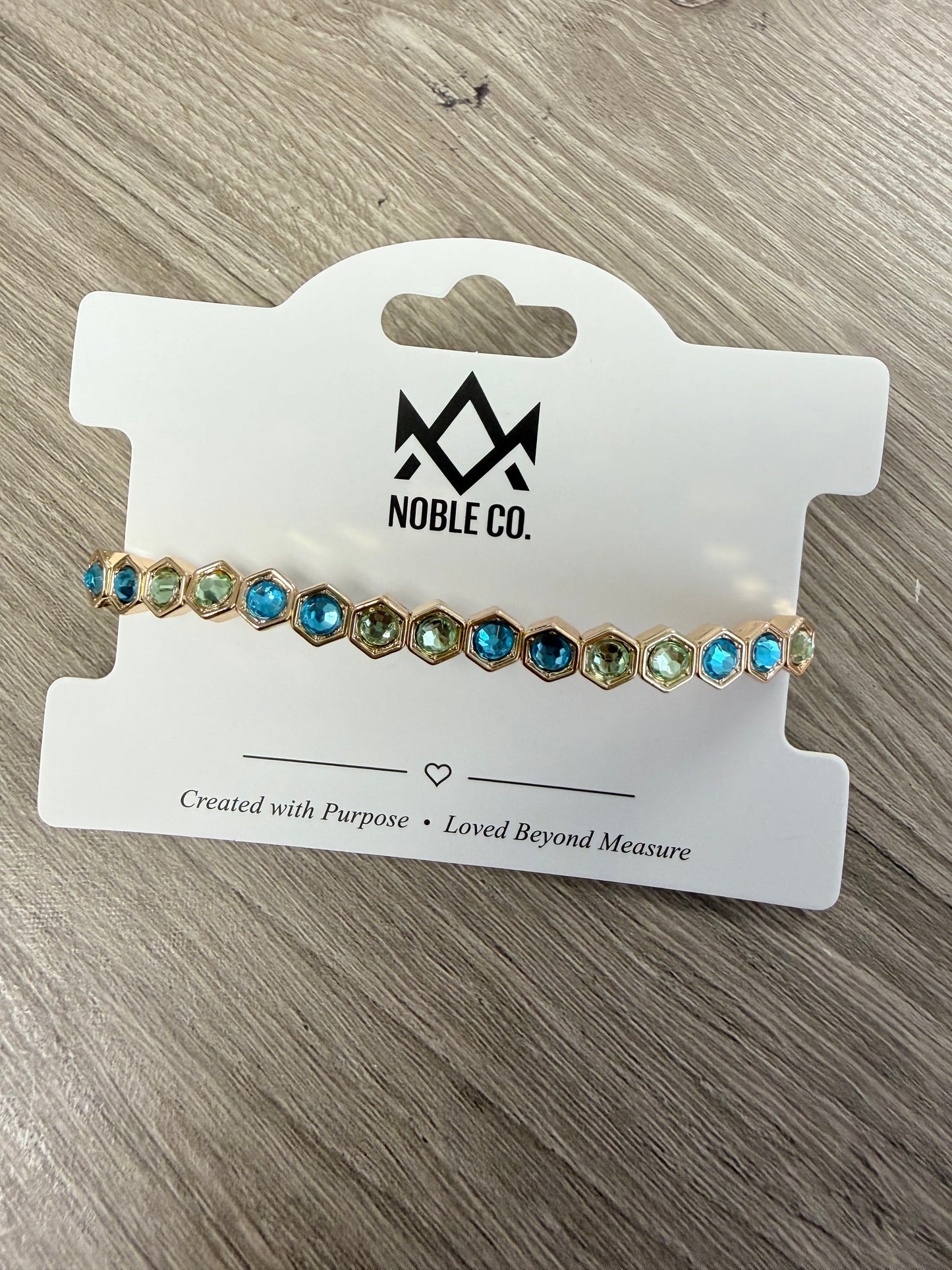 Harper Crystal Stretch Bracelet by Noble Co. featuring blue faceted crystal stones in gold hexagon settings on a 7-inch stretch band.
